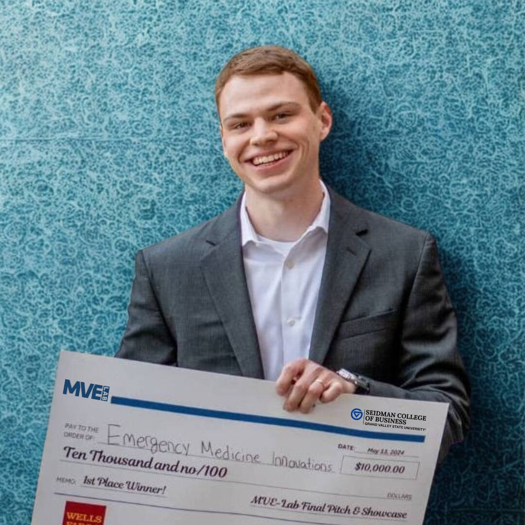 Male in a gray suit jacket holding a big check